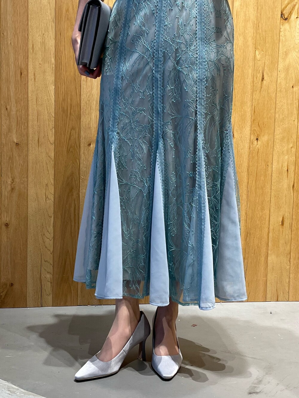 グレー系のクラッチバッグ、グレー系のパンプス、グリーン系のドレスを着用したレディースの冬コーディネートの7枚目の写真