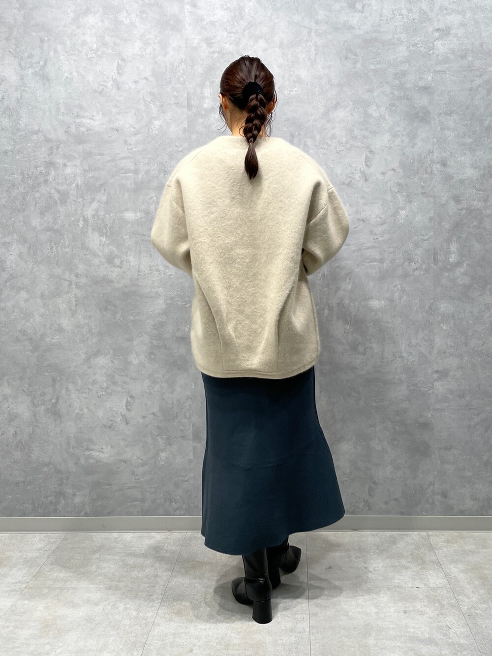 ホワイト系のカーディガン/ボレロ、ブラック系のブーツ、グリーン系のスカートを着用したレディースの冬コーディネートの3枚目の写真