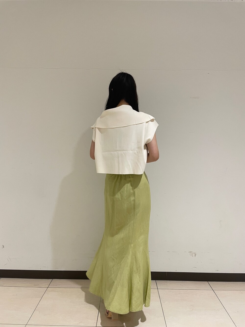 ホワイト系のニット/セーター、ベージュ系のサンダル、グリーン系のスカートを着用したレディースの春コーディネートの6枚目の写真