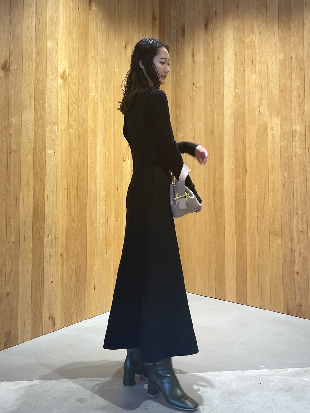 ベージュ系のハンドバッグ、グリーン系のブーツ、ブラック系のスカートを着用したレディースの秋コーディネートの4枚目の写真