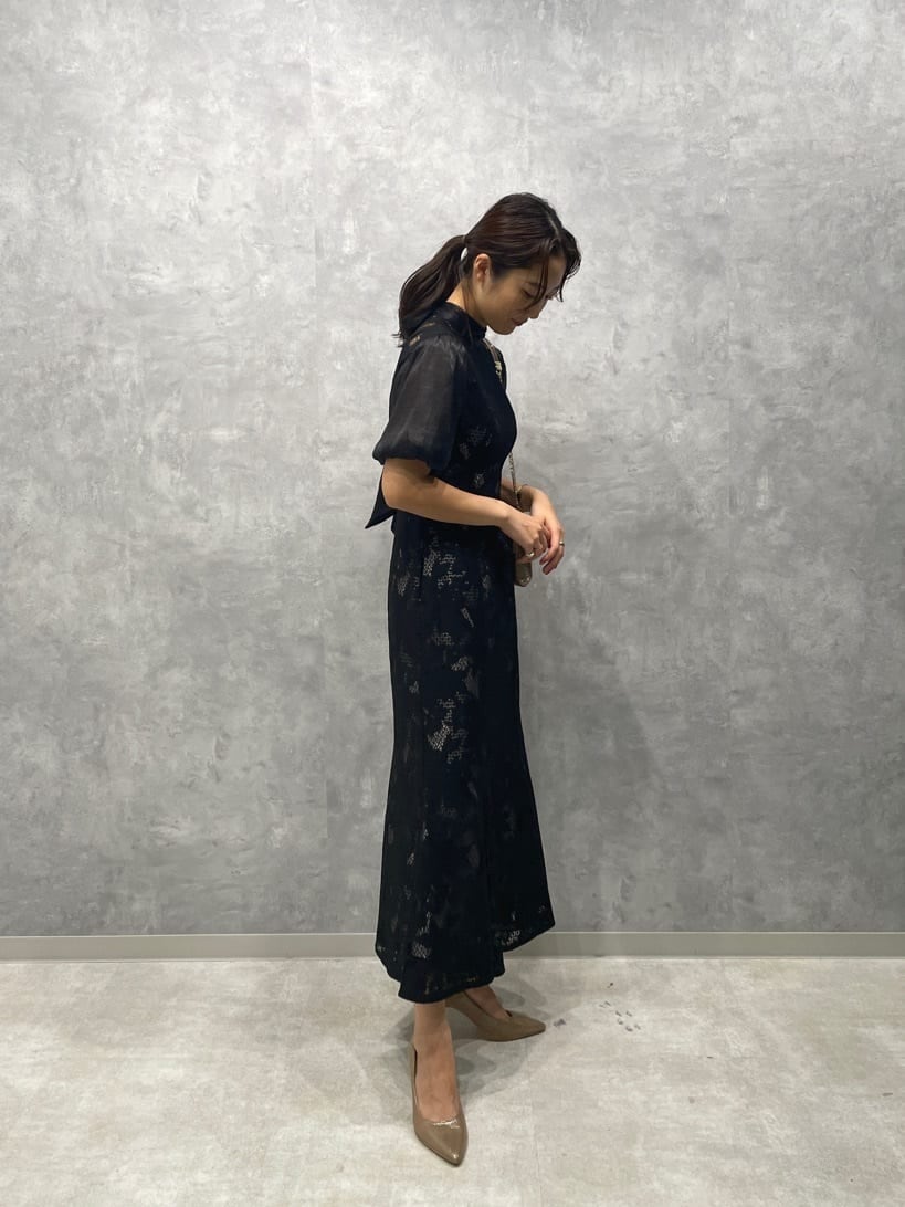 ゴールド系のパンプス、ゴールド系のクラッチバッグ、ブラック系のドレスを着用したレディースの秋コーディネートの5枚目の写真