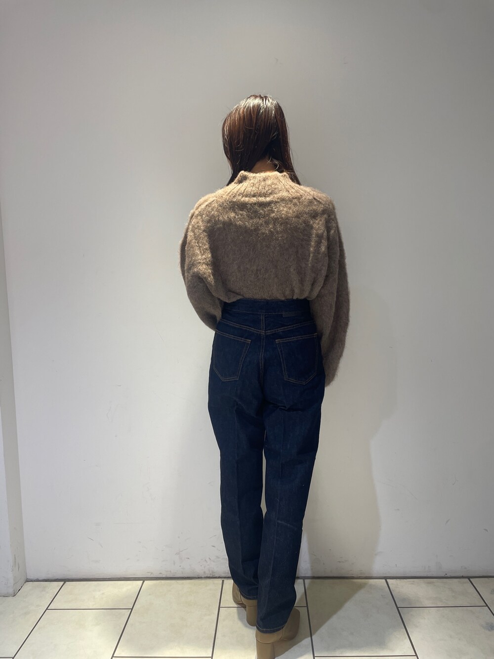 ブラウン系のニット/セーター、ベージュ系のブーツ、ブルー系のデニムパンツを着用したレディースの秋コーディネートの3枚目の写真