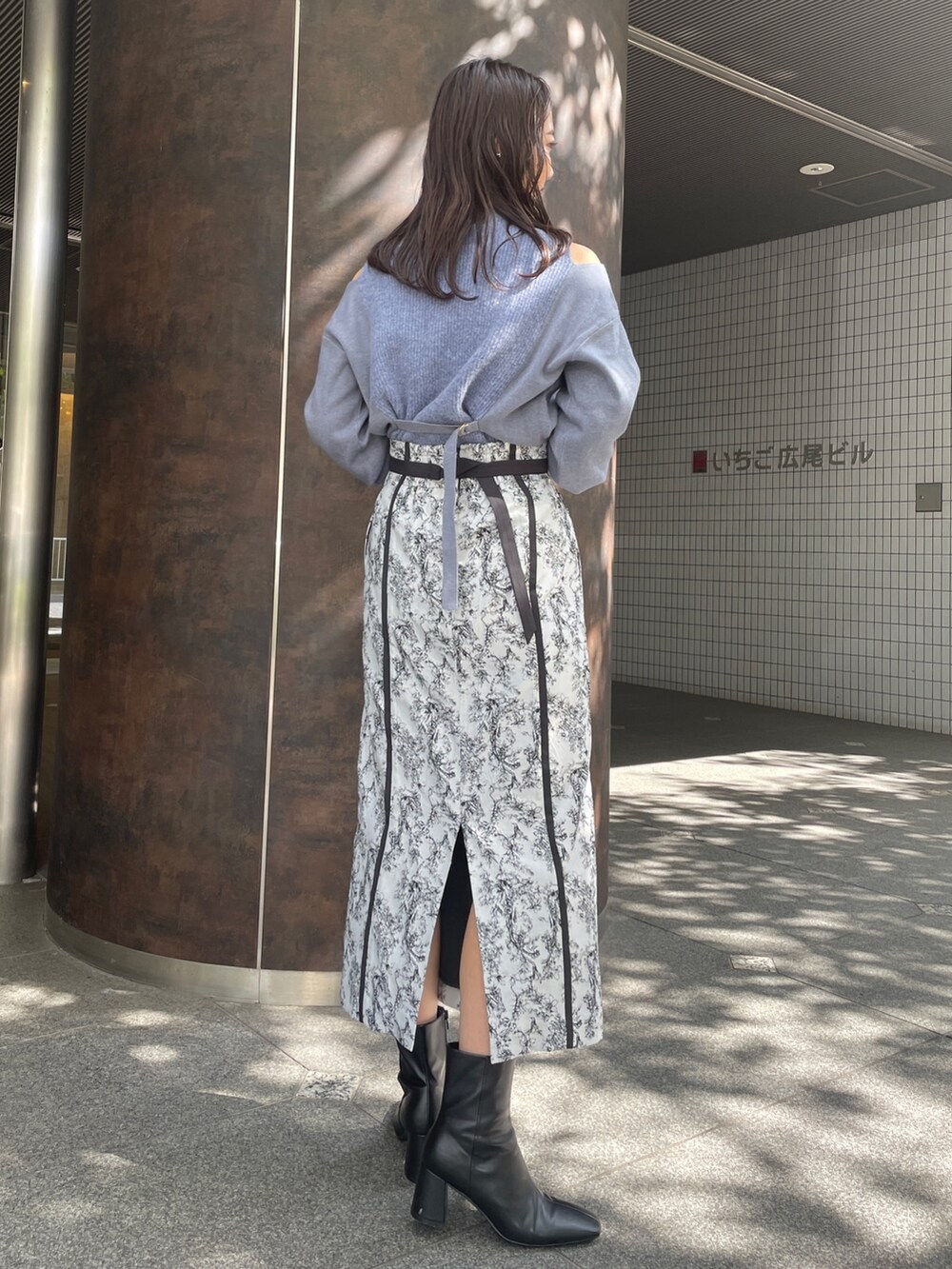 ブラック系のハンドバッグ、ブラック系のスカート、ブラック系のブーツを着用したレディースの秋コーディネートの5枚目の写真