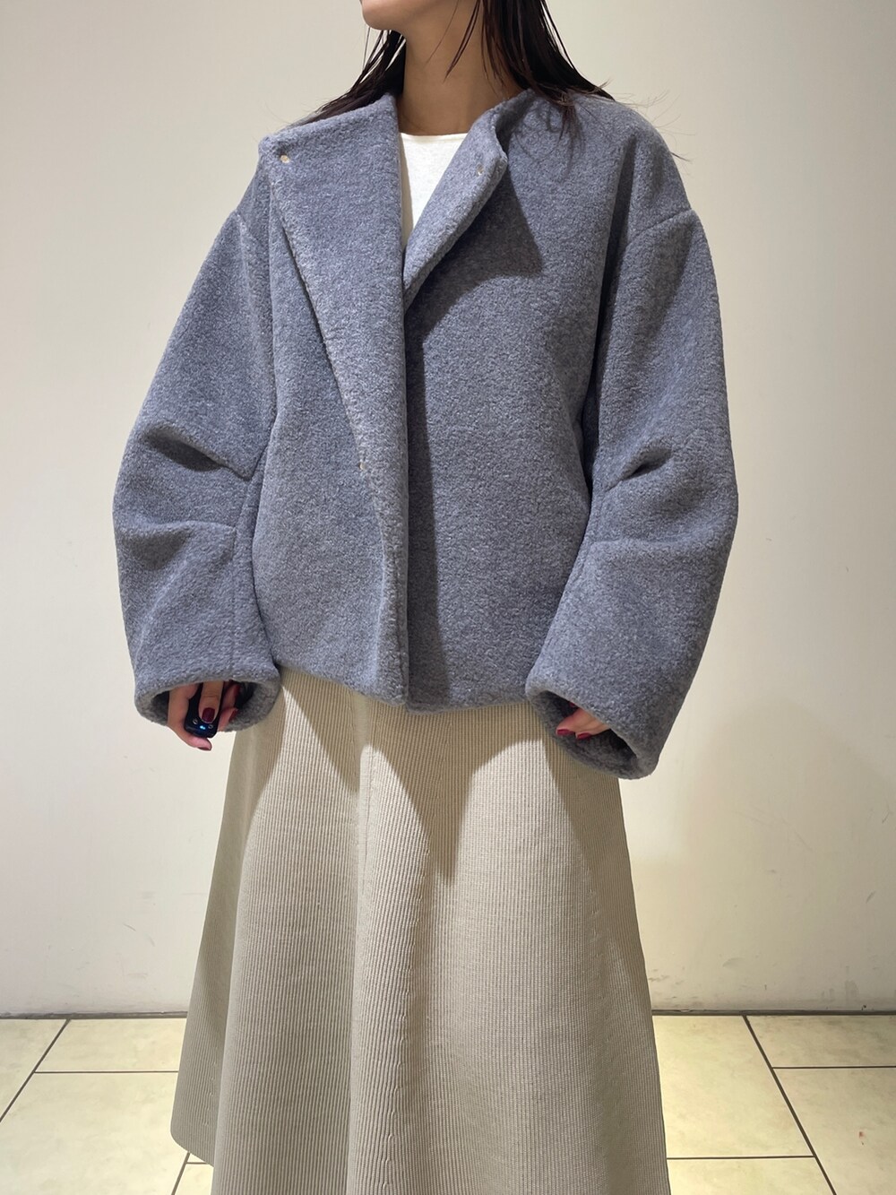 グレー系のブルゾン、ホワイト系のブーツ、ホワイト系のジャンパースカートを着用したレディースの秋コーディネートの6枚目の写真