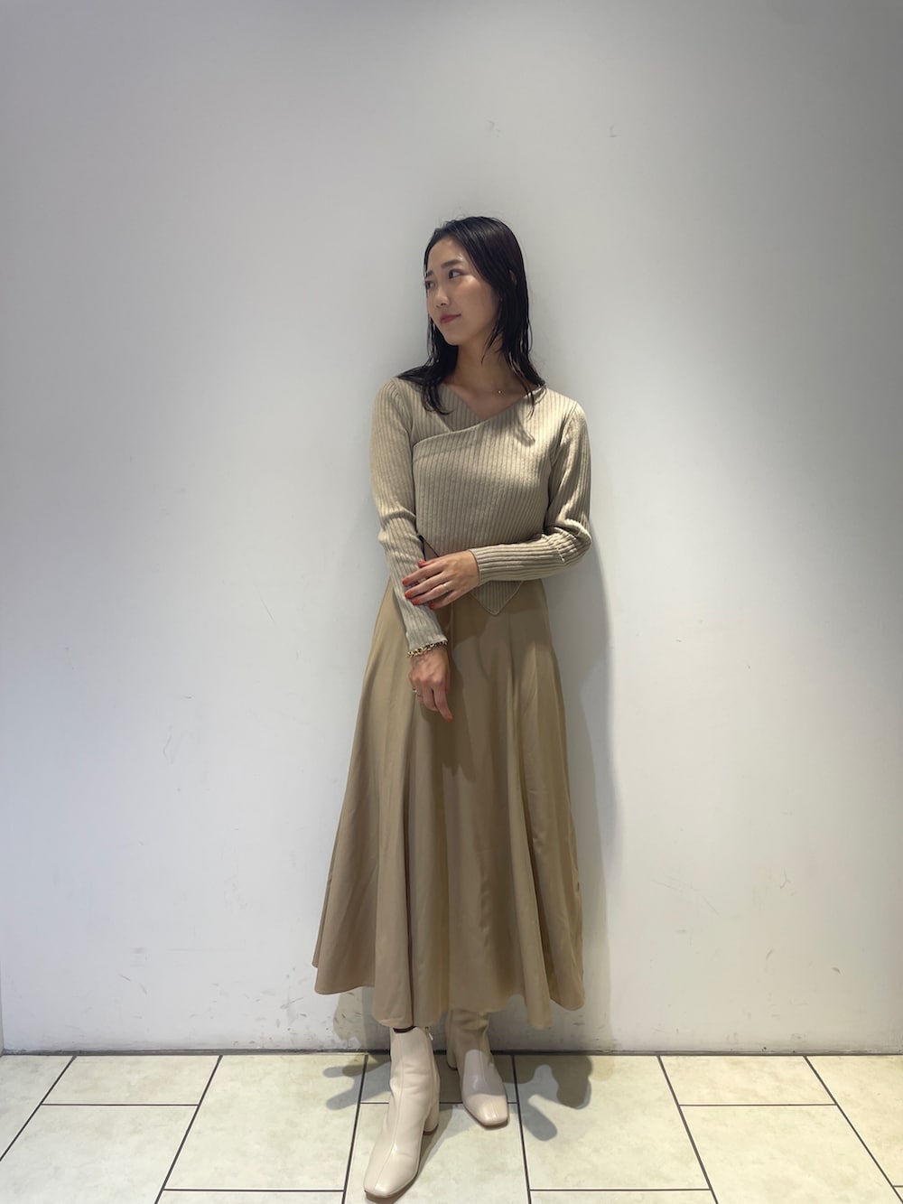 ベージュ系のワンピース、ホワイト系のブーツを着用したレディースの秋コーディネートの2枚目の写真