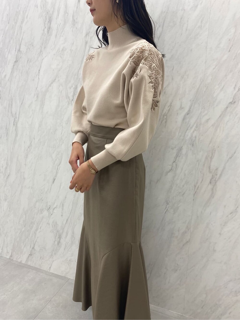 ブラック系のブーツ、ベージュ系のスカート、ホワイト系のニット/セーターを着用したレディースの秋コーディネートの6枚目の写真