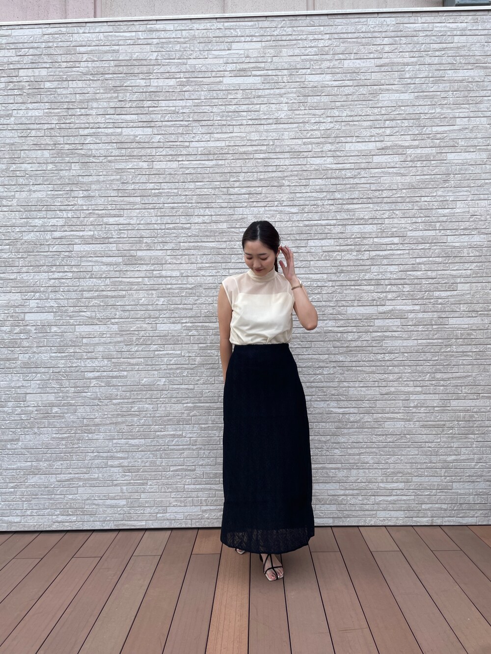 ブラック系のスカート、ホワイト系のTシャツ/カットソー、ブラック系のサンダルを着用したレディースの夏コーディネートの3枚目の写真