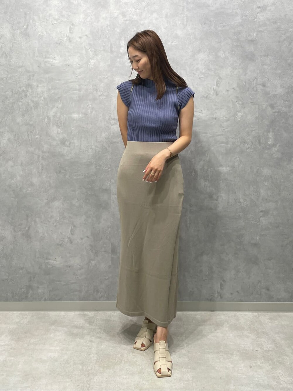 ホワイト系のサンダル、ベージュ系のスカート、ブルー系のニット/セーターを着用したレディースの夏コーディネートの2枚目の写真