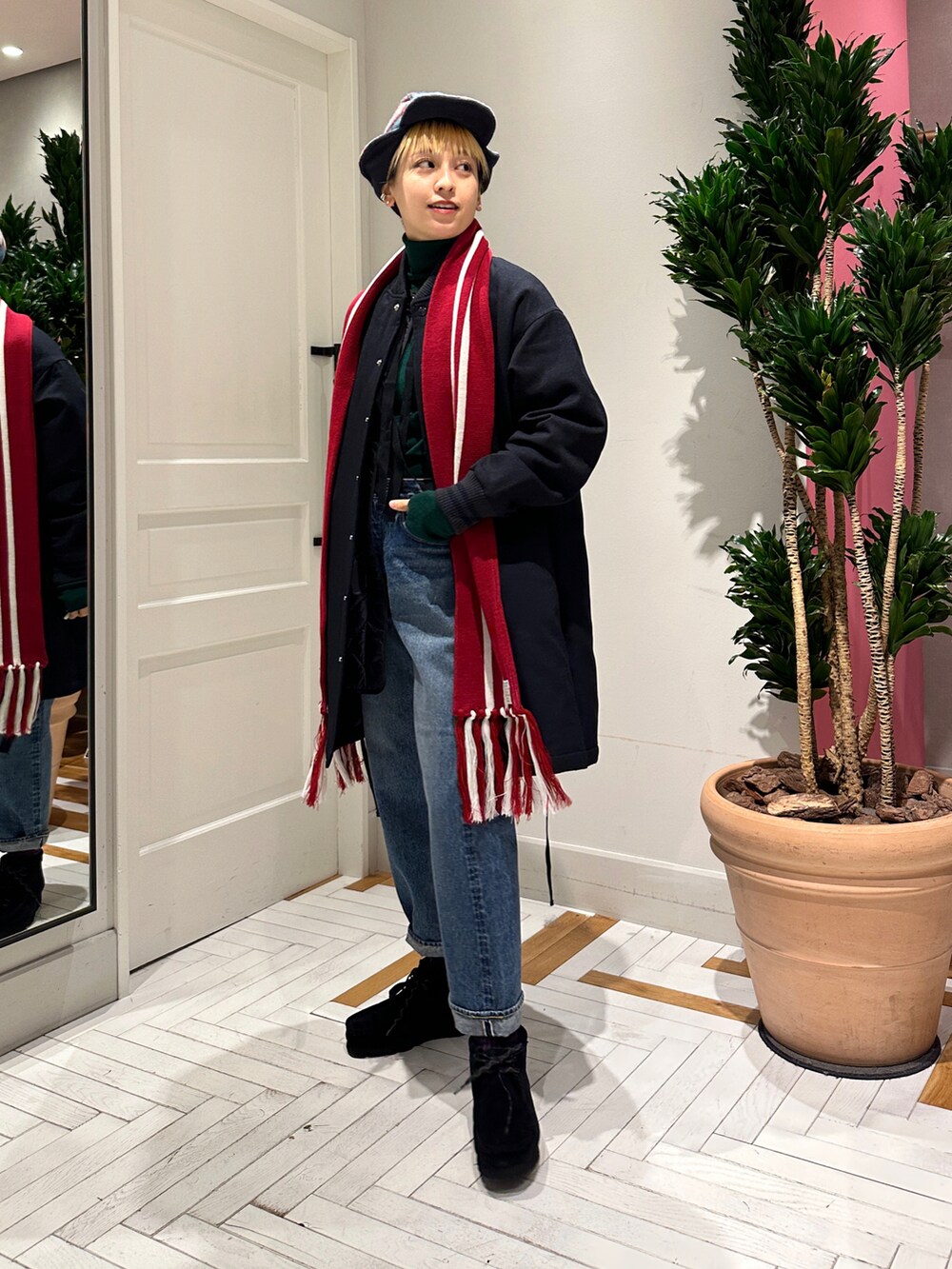 ブルー系のデニムパンツ、ブラック系のブーツ、グリーン系のニット/セーターを着用したレディースの冬コーディネートの5枚目の写真