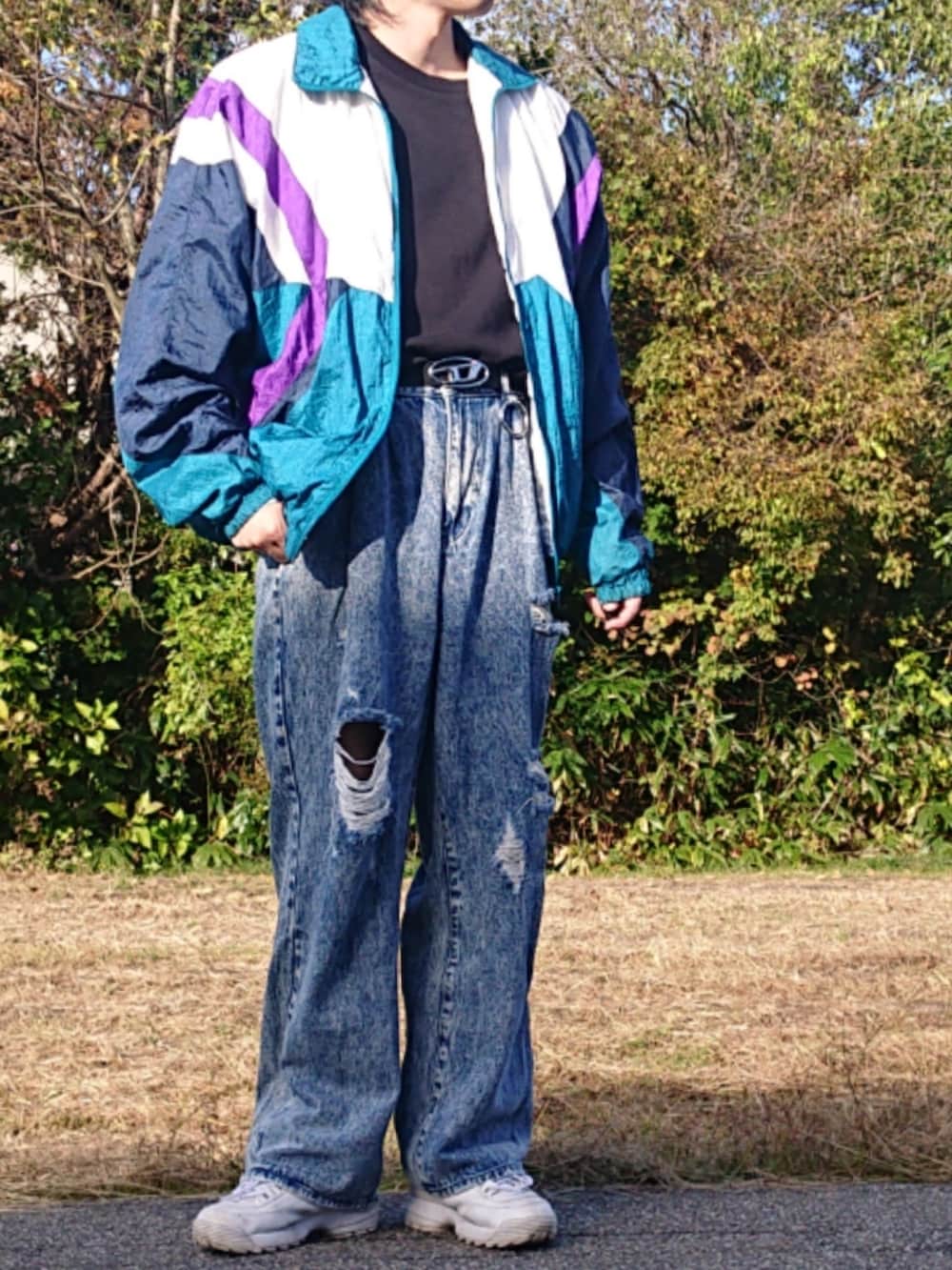 ホワイト系のスニーカー、ブルー系のデニムパンツを着用したメンズの秋コーディネートの2枚目の写真