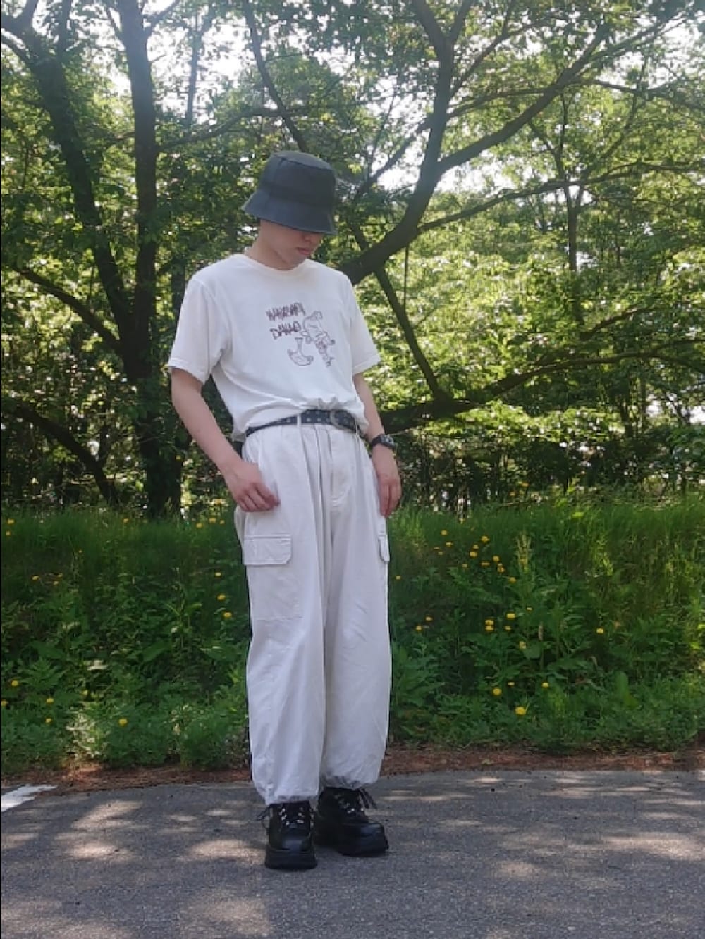 ホワイト系のカーゴパンツ、ブラック系のスニーカー、ブラック系のハットを着用したメンズの夏コーディネートの2枚目の写真