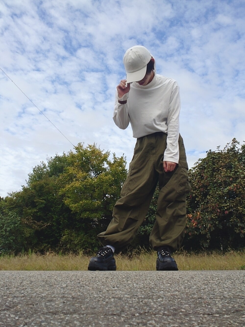 ブラック系のスニーカー、ホワイト系のTシャツ/カットソー、グリーン系のカーゴパンツを着用したメンズの秋コーディネートの2枚目の写真