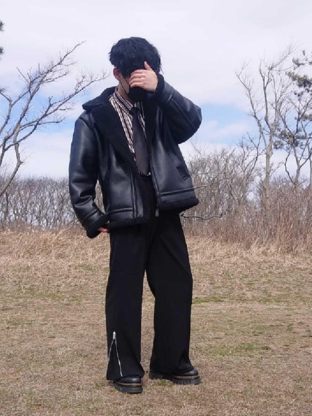 ブラック系のスラックス、ブラック系のブーツを着用したメンズの春コーディネートの2枚目の写真