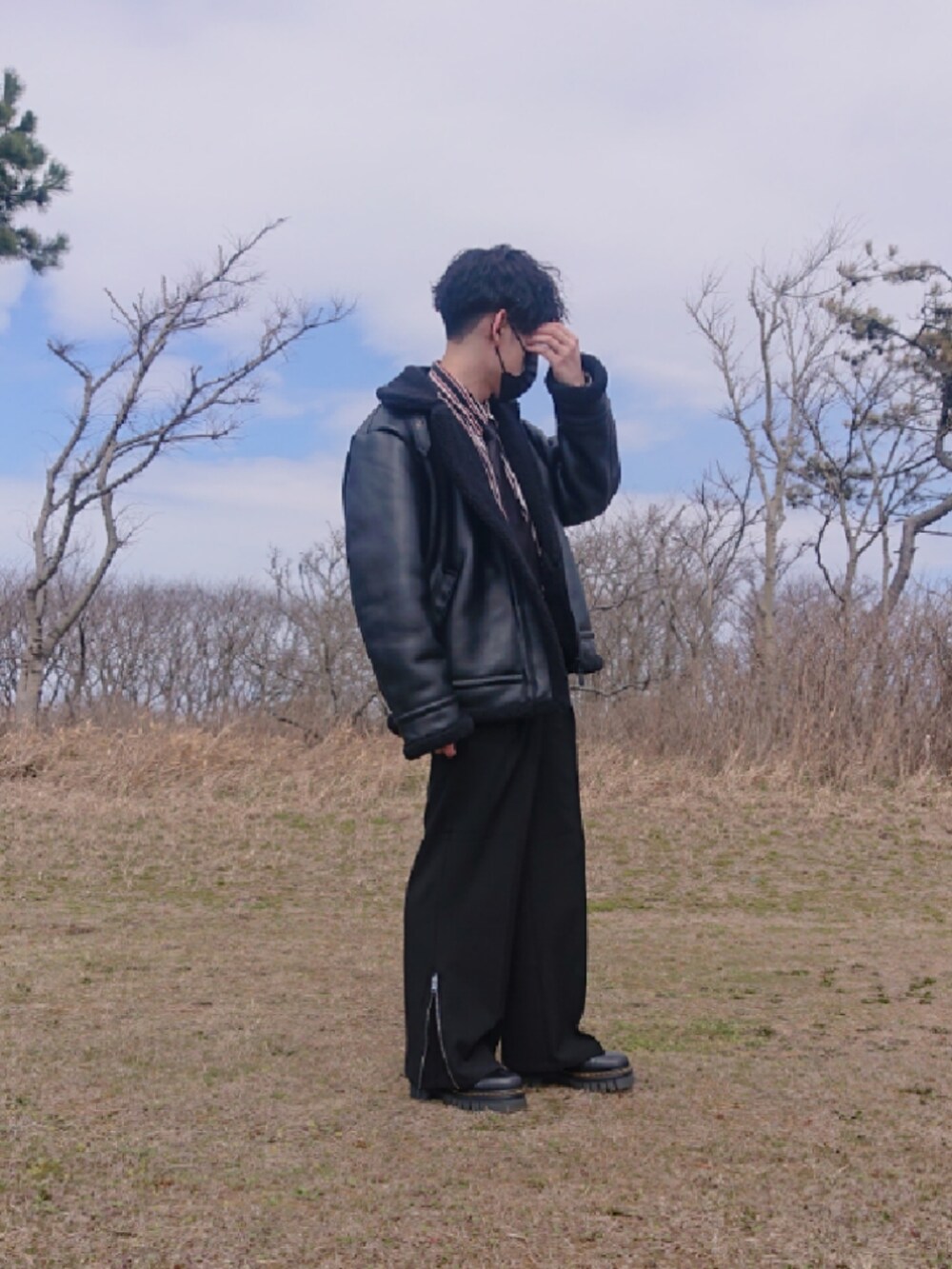 ブラック系のスラックス、ブラック系のブーツを着用したメンズの春コーディネートの3枚目の写真