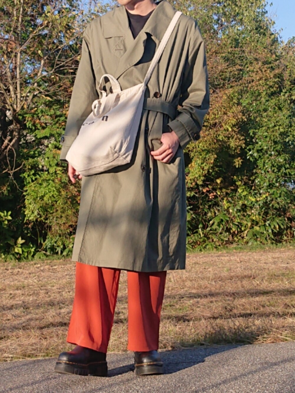 オレンジ系のスラックス、ブラック系のブーツを着用したメンズの秋コーディネートの2枚目の写真