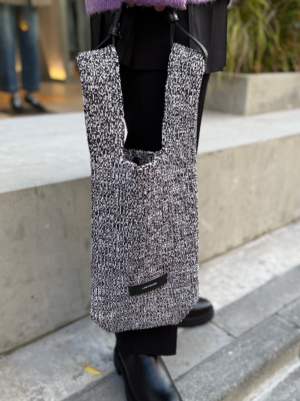 パープル系のカーディガン/ボレロ、ホワイト系のニット/セーター、ブラック系のスカートを着用したレディースの秋コーディネートの3枚目の写真