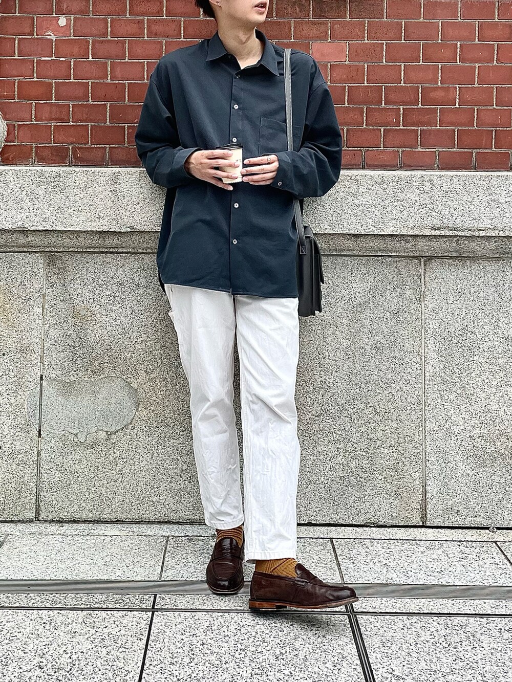 ホワイト系のデニムパンツ、ブラウン系のローファー、グレー系のショルダーバッグを着用したメンズの秋コーディネートの2枚目の写真