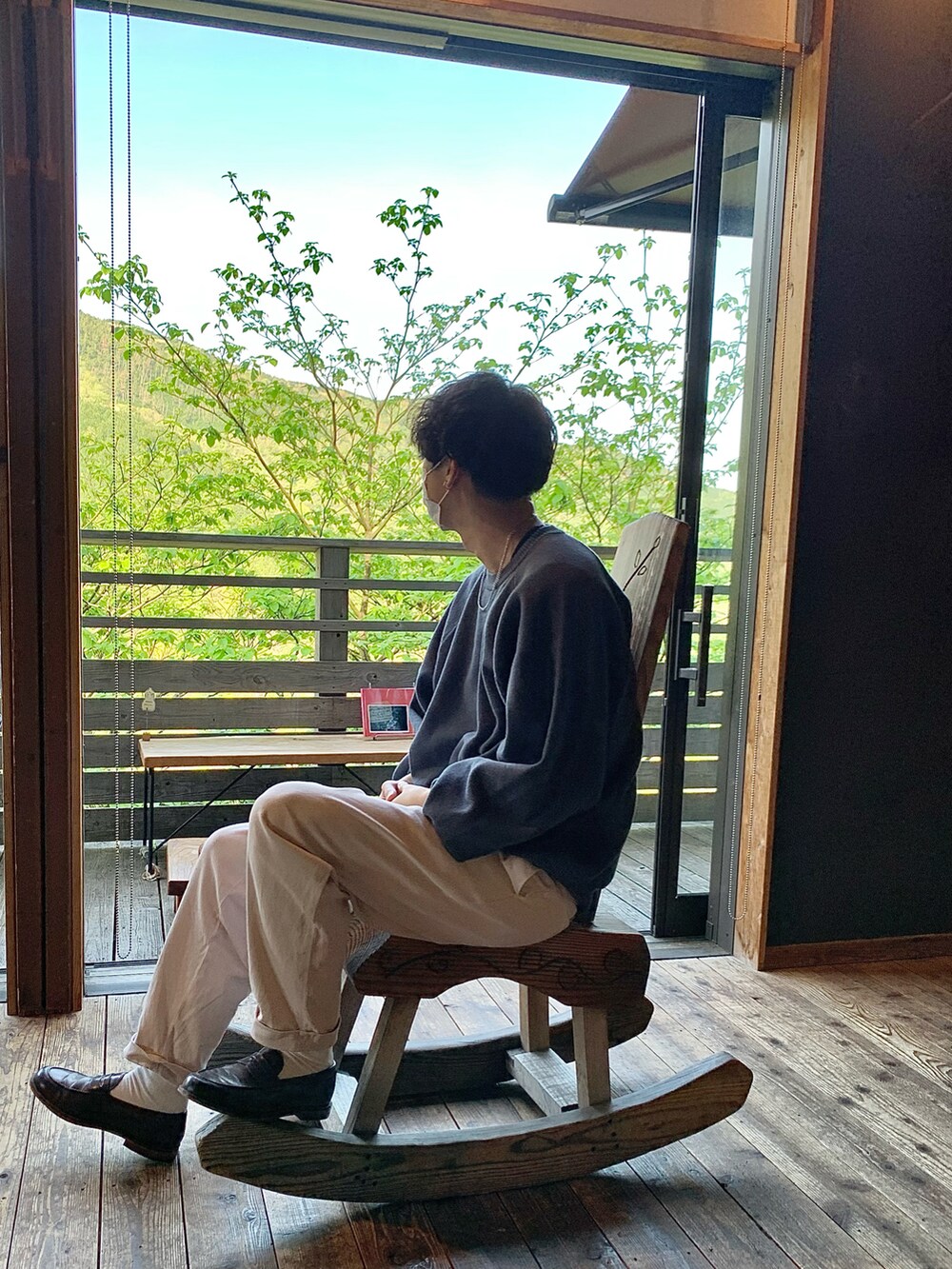 ホワイト系のチノパンツ、ブラウン系のローファー、ブルー系のニット/セーターを着用したメンズの春コーディネートの2枚目の写真