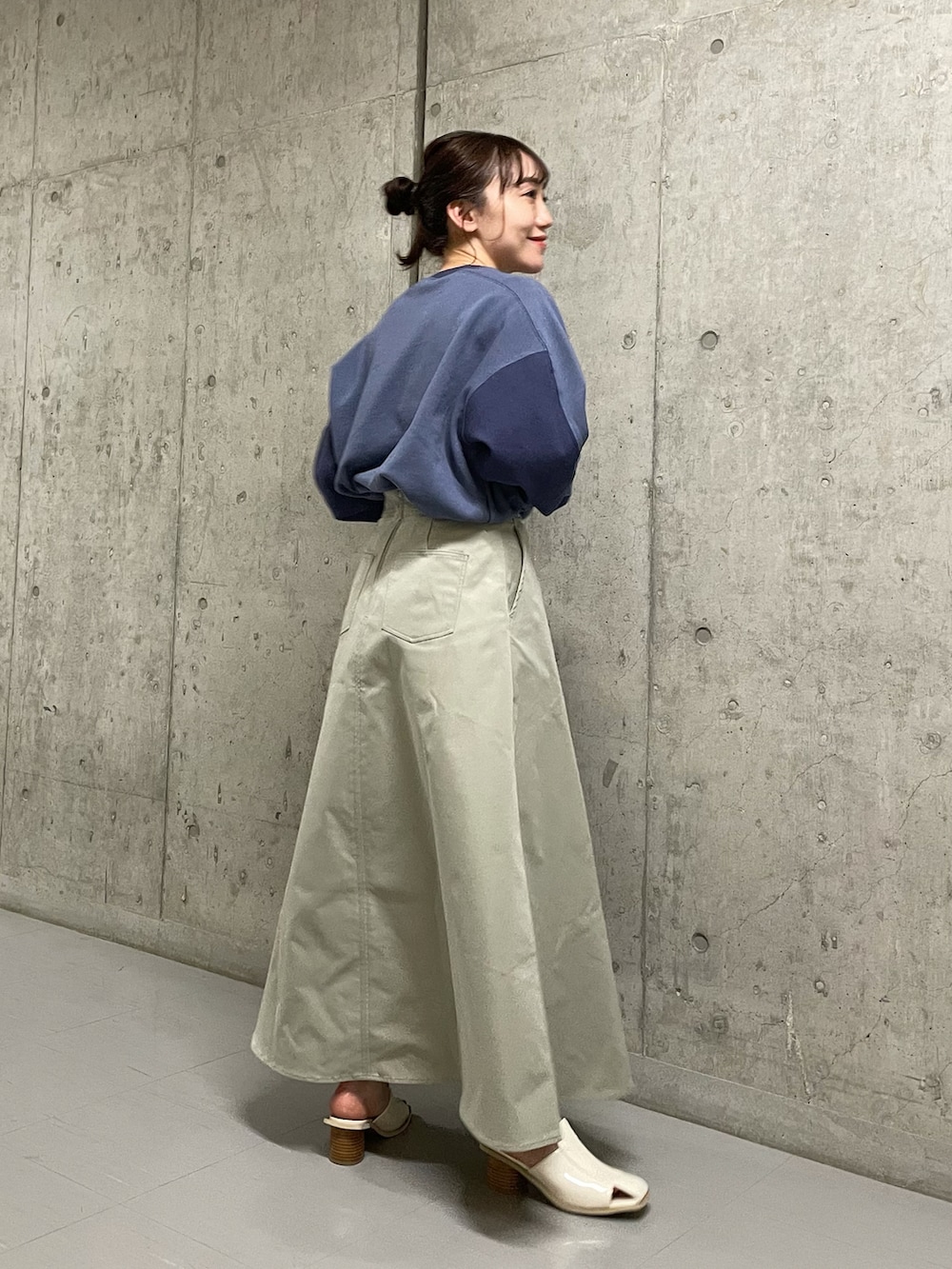 ブルー系のスウェット、グリーン系のスカート、ホワイト系のサンダルを着用したレディースの春コーディネートの2枚目の写真