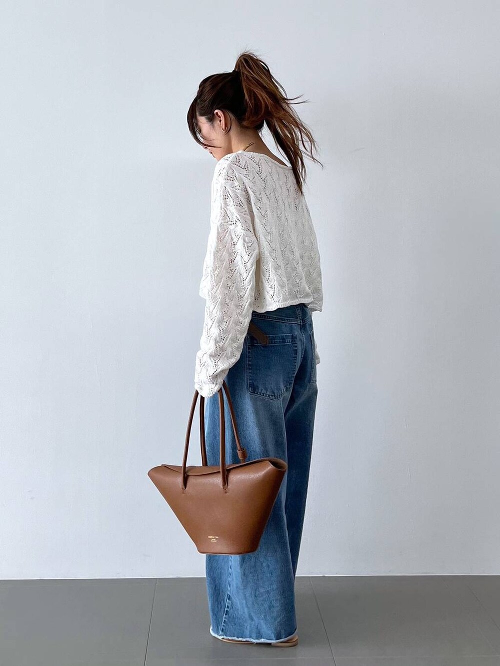 ブルー系のデニムパンツ、イエロー系のハンドバッグ、グレー系のベルトを着用したレディースの春コーディネートの4枚目の写真