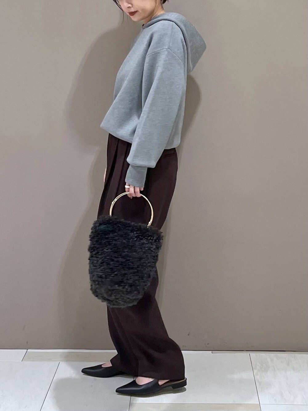 グレー系のハンドバッグ、ブラック系のパンプス、グレー系のパーカーを着用したレディースの秋コーディネートの4枚目の写真