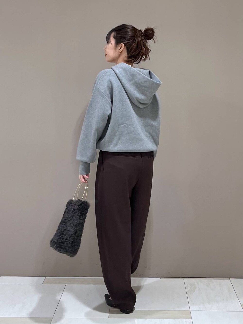 グレー系のハンドバッグ、ブラック系のパンプス、グレー系のパーカーを着用したレディースの秋コーディネートの3枚目の写真