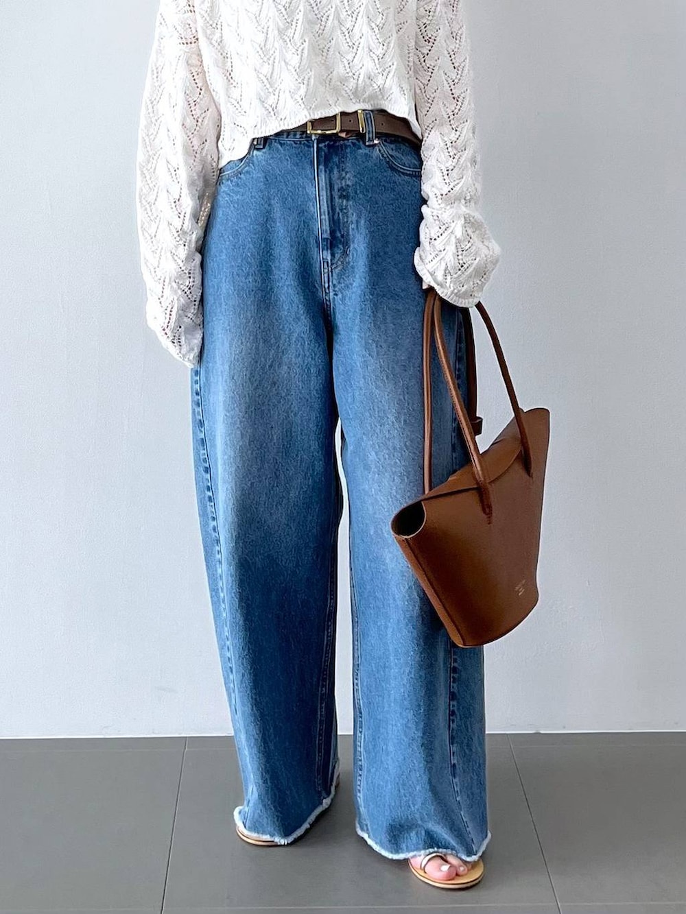 ブルー系のデニムパンツ、イエロー系のハンドバッグ、グレー系のベルトを着用したレディースの春コーディネートの3枚目の写真