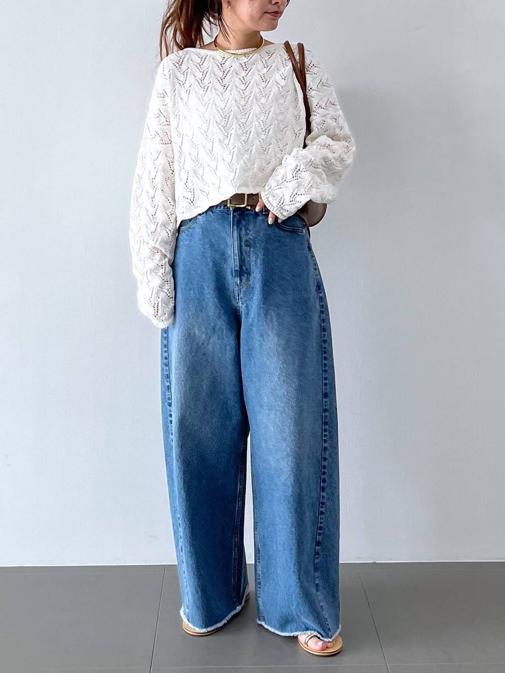 ブルー系のデニムパンツ、イエロー系のハンドバッグ、グレー系のベルトを着用したレディースの春コーディネートの2枚目の写真