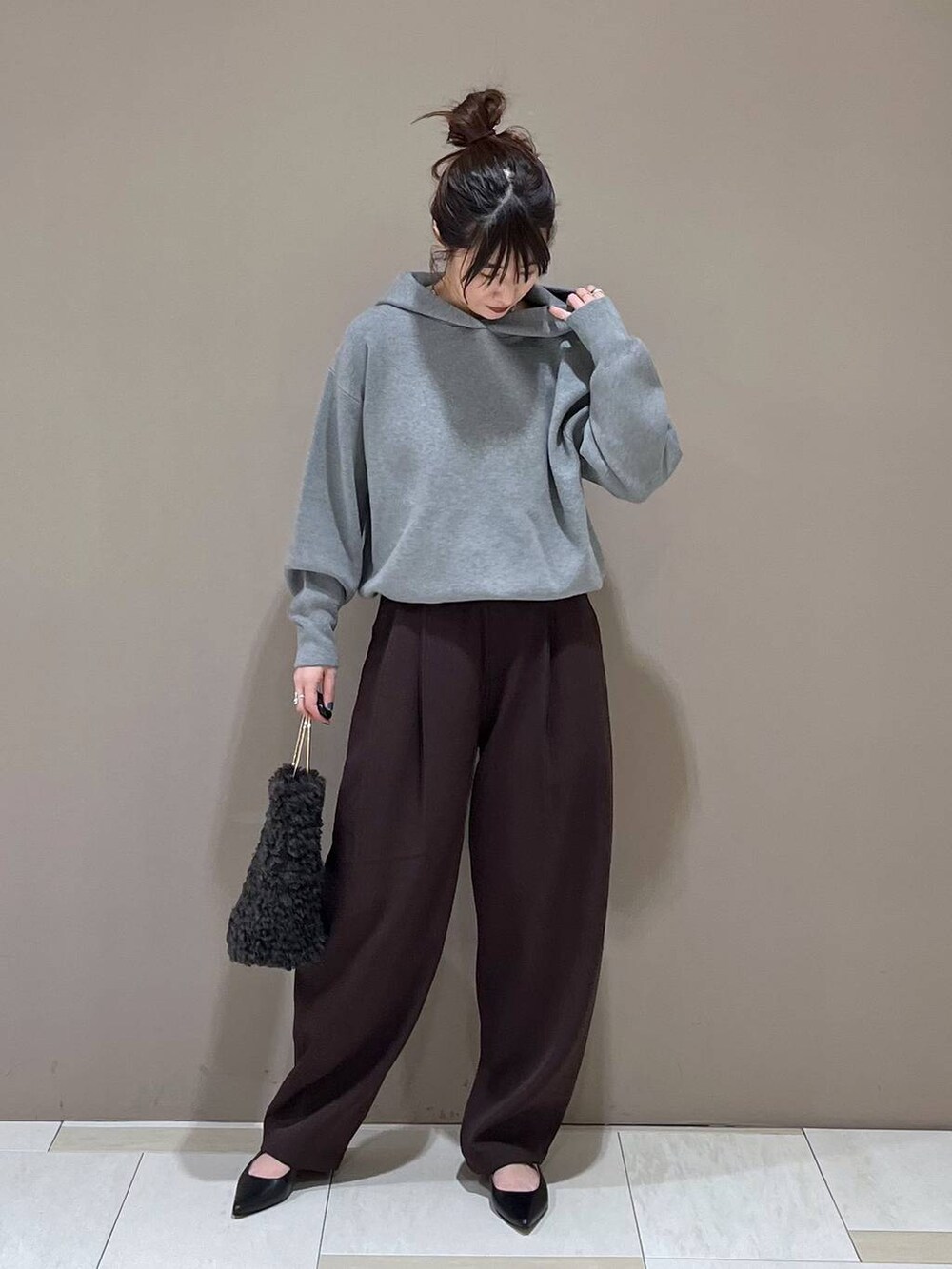 グレー系のハンドバッグ、ブラック系のパンプス、グレー系のパーカーを着用したレディースの秋コーディネートの2枚目の写真