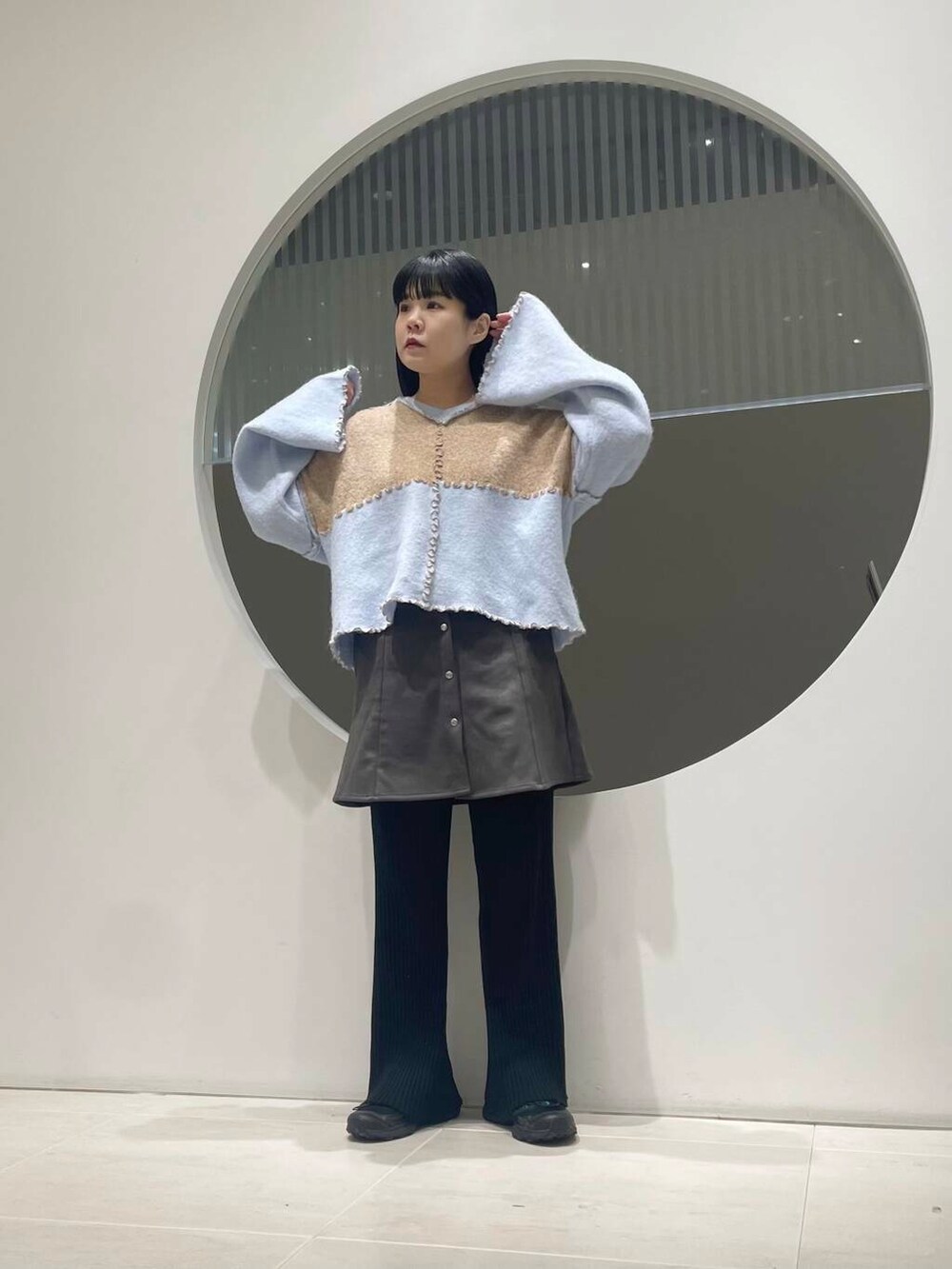 ブラック系のスニーカー、グレー系のスカート、ベージュ系のニット/セーターを着用したレディースの冬コーディネートの2枚目の写真