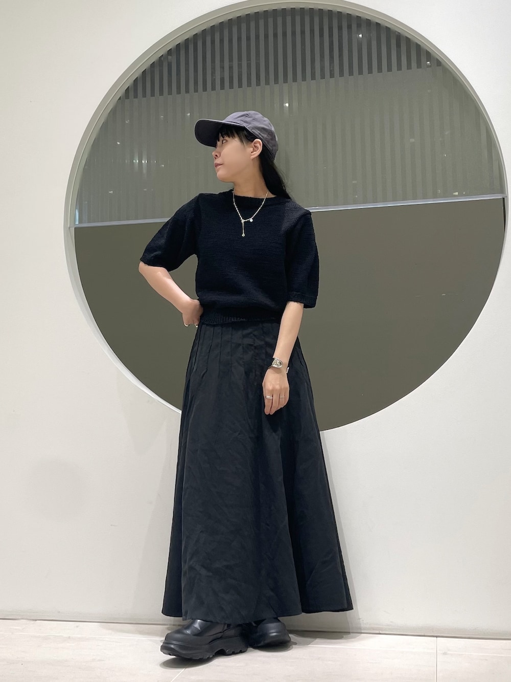 ブラック系のスカート、ブラック系のブーツ、ブラック系のニット/セーターを着用したレディースの秋コーディネートの2枚目の写真