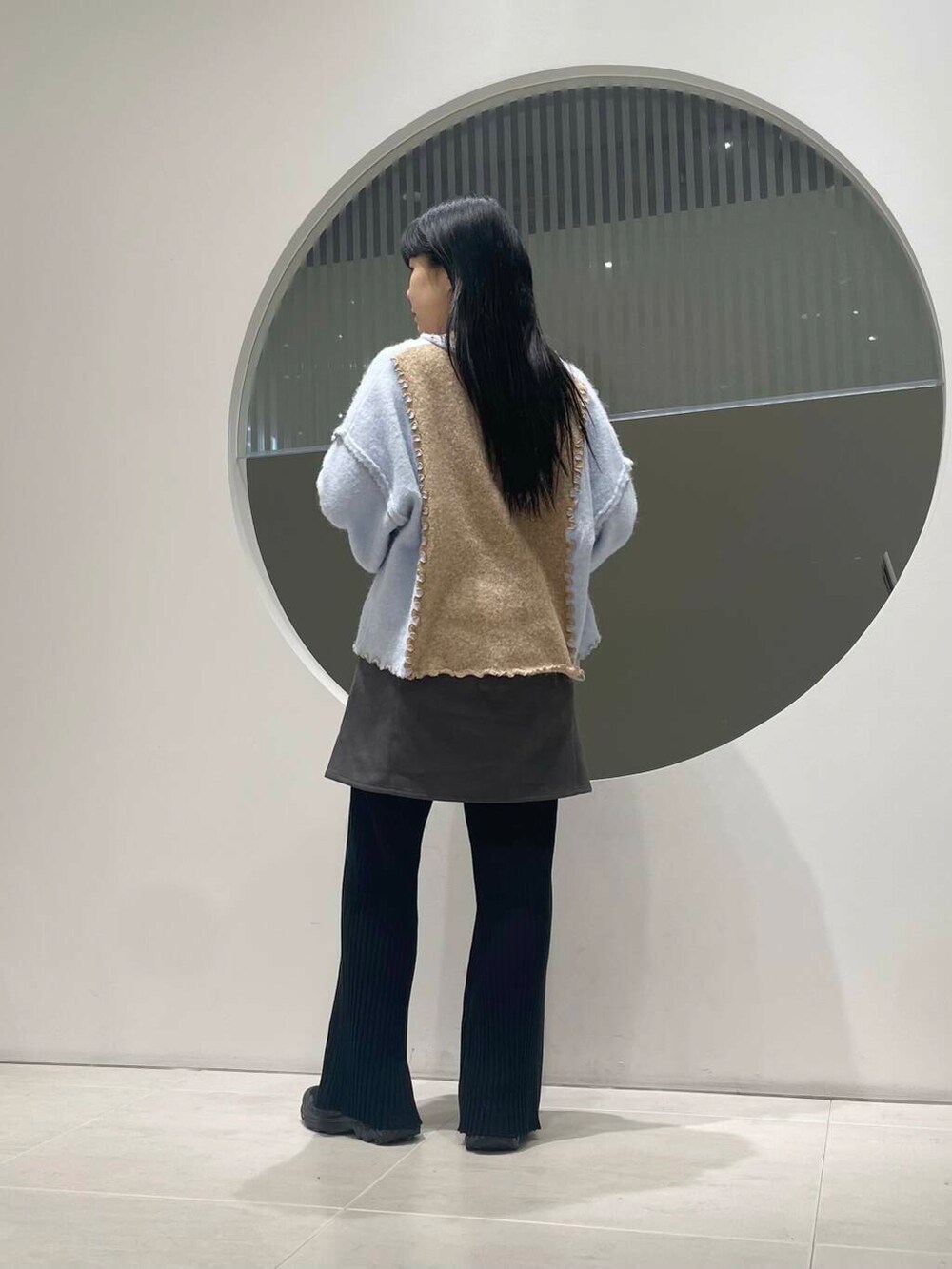 ブラック系のスニーカー、グレー系のスカート、ベージュ系のニット/セーターを着用したレディースの冬コーディネートの3枚目の写真