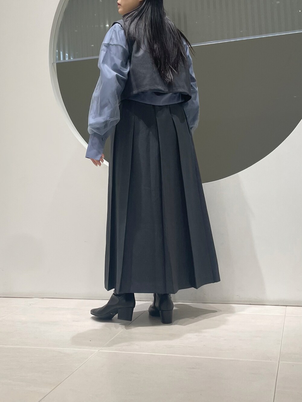 グレー系のワンピース、ブラック系のブーツ、ブルー系のシャツ/ブラウスを着用したレディースの冬コーディネートの3枚目の写真