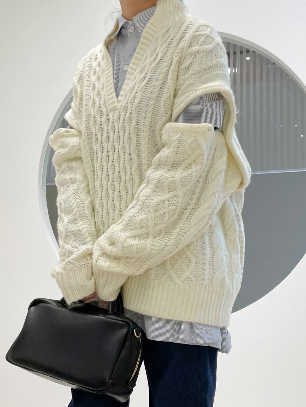 ホワイト系のニット/セーター、ブラック系のボストンバッグ、ブラック系のブーツを着用したレディースの冬コーディネートの4枚目の写真