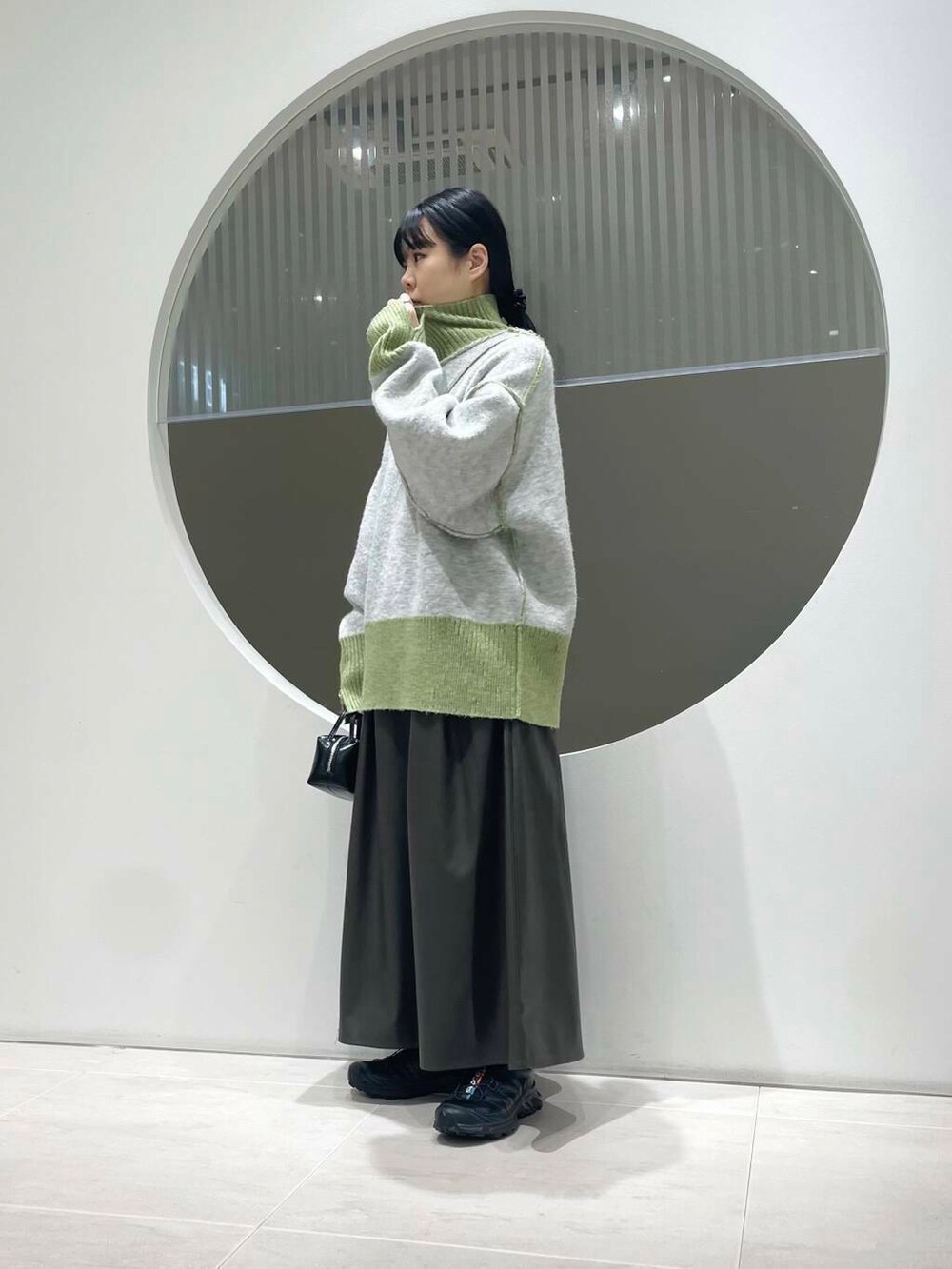 ブラック系のスニーカー、ブラウン系のスカート、グリーン系のニット/セーターを着用したレディースの冬コーディネートの3枚目の写真