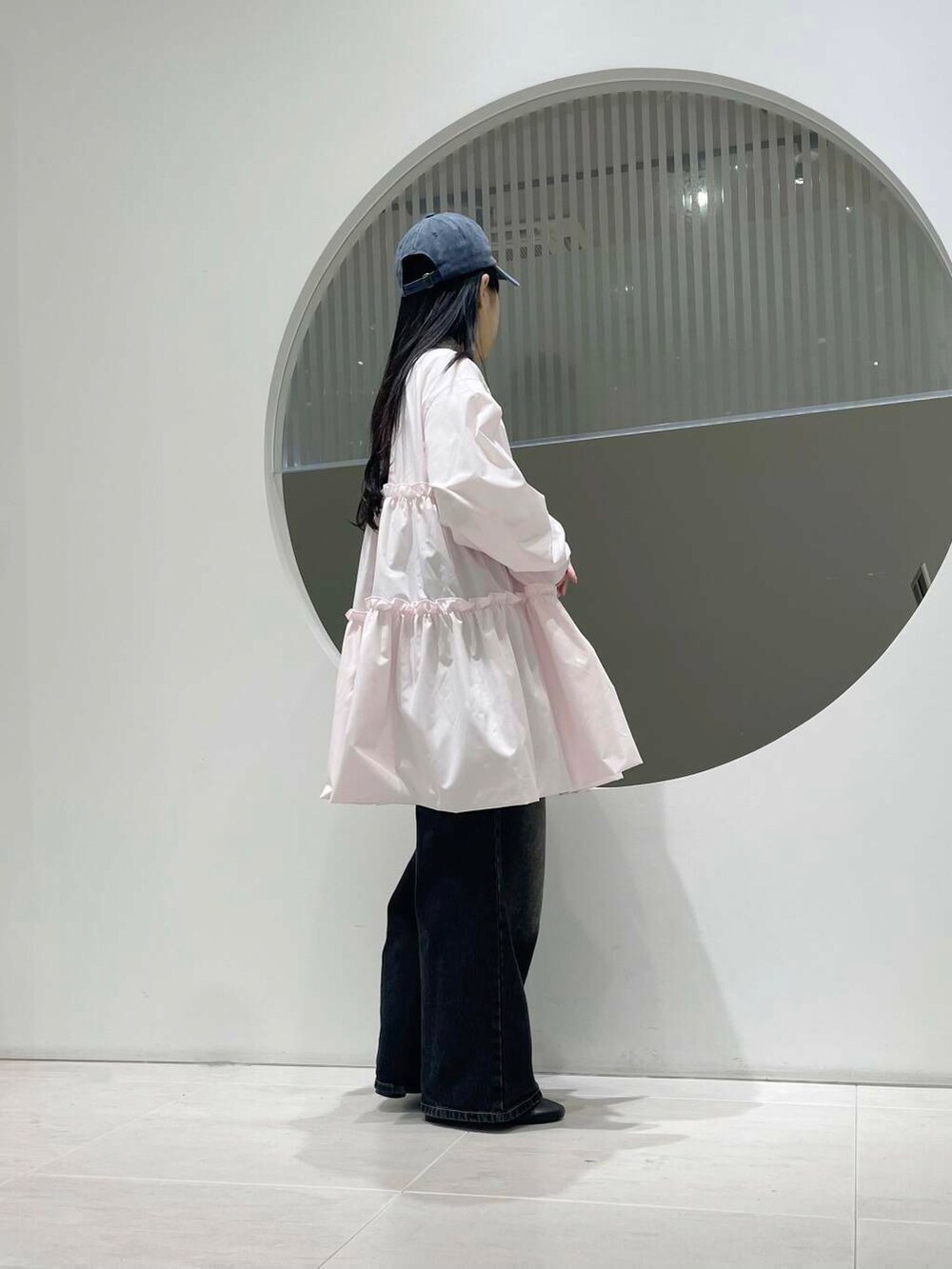 ブラック系のブーツ、ブラック系のデニムパンツ、ピンク系のワンピースを着用したレディースの冬コーディネートの2枚目の写真