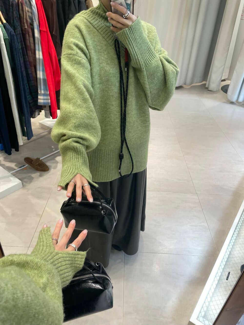 ブラック系のスニーカー、ブラウン系のスカート、グリーン系のニット/セーターを着用したレディースの冬コーディネートの4枚目の写真