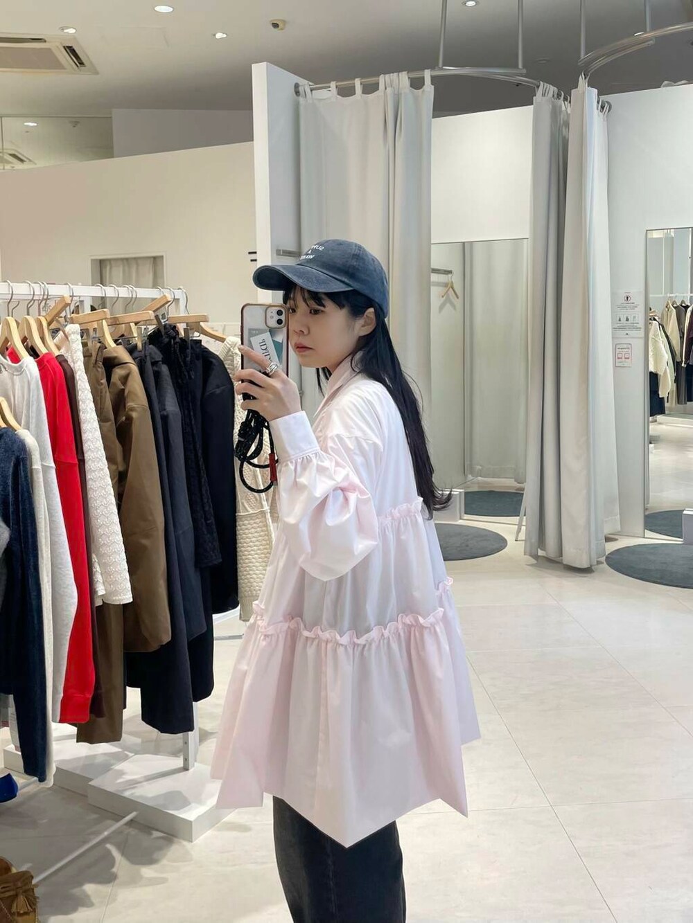 ブラック系のブーツ、ブラック系のデニムパンツ、ピンク系のワンピースを着用したレディースの冬コーディネートの4枚目の写真