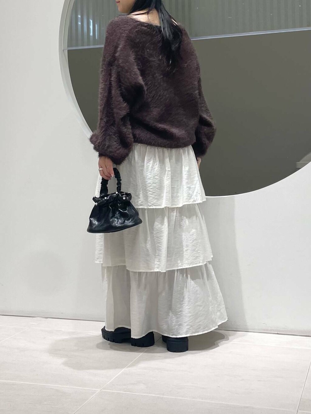ブラック系のブーツ、ホワイト系のスカート、ブラウン系のニット/セーターを着用したレディースの冬コーディネートの3枚目の写真