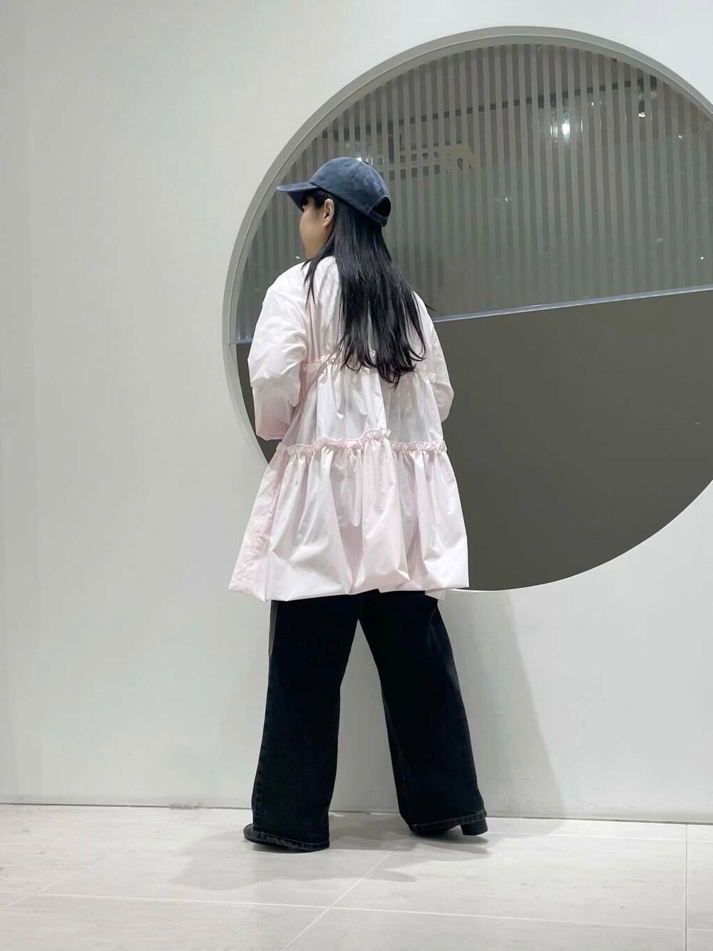 ブラック系のブーツ、ブラック系のデニムパンツ、ピンク系のワンピースを着用したレディースの冬コーディネートの3枚目の写真