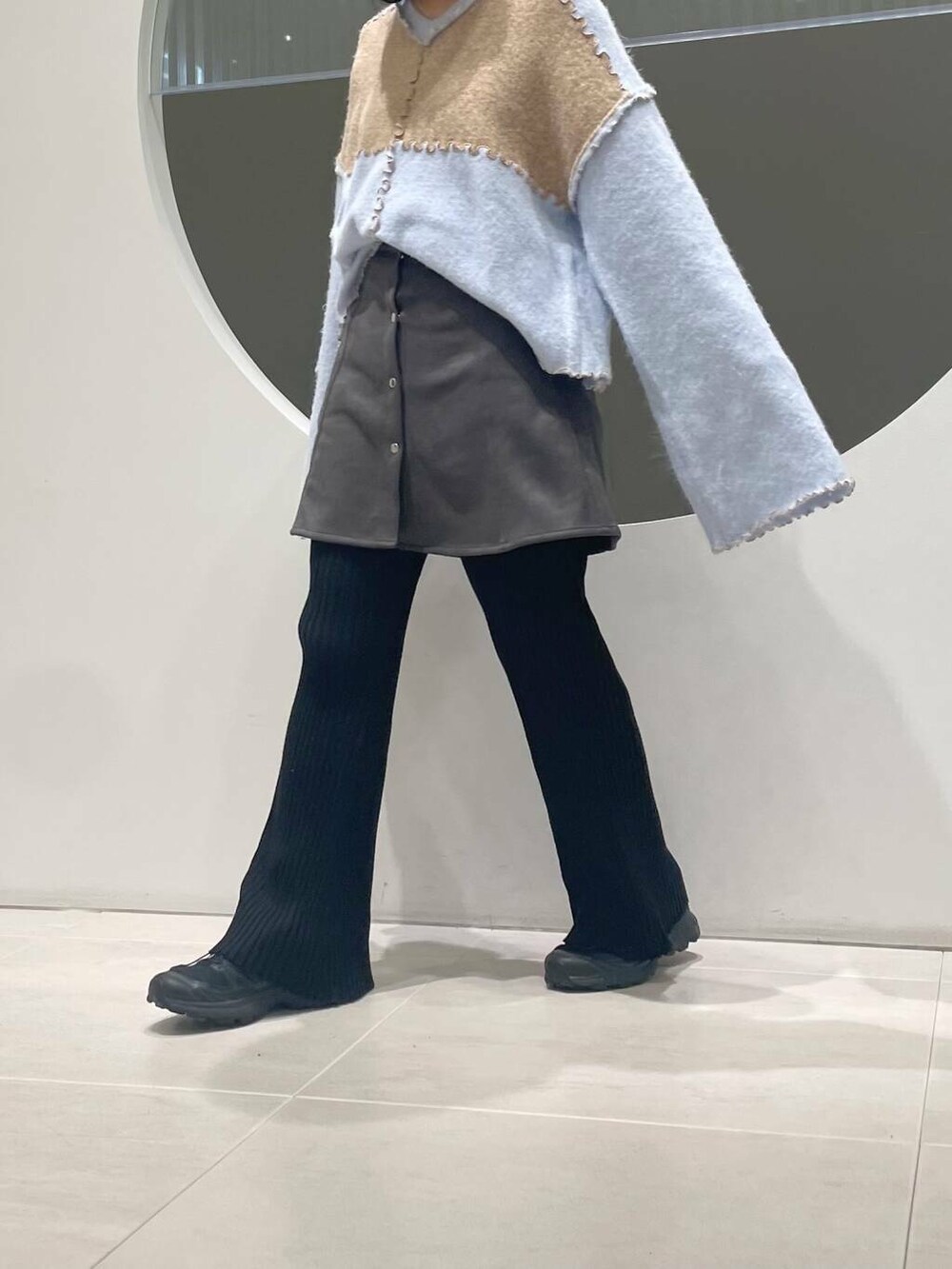 ブラック系のスニーカー、グレー系のスカート、ベージュ系のニット/セーターを着用したレディースの冬コーディネートの4枚目の写真