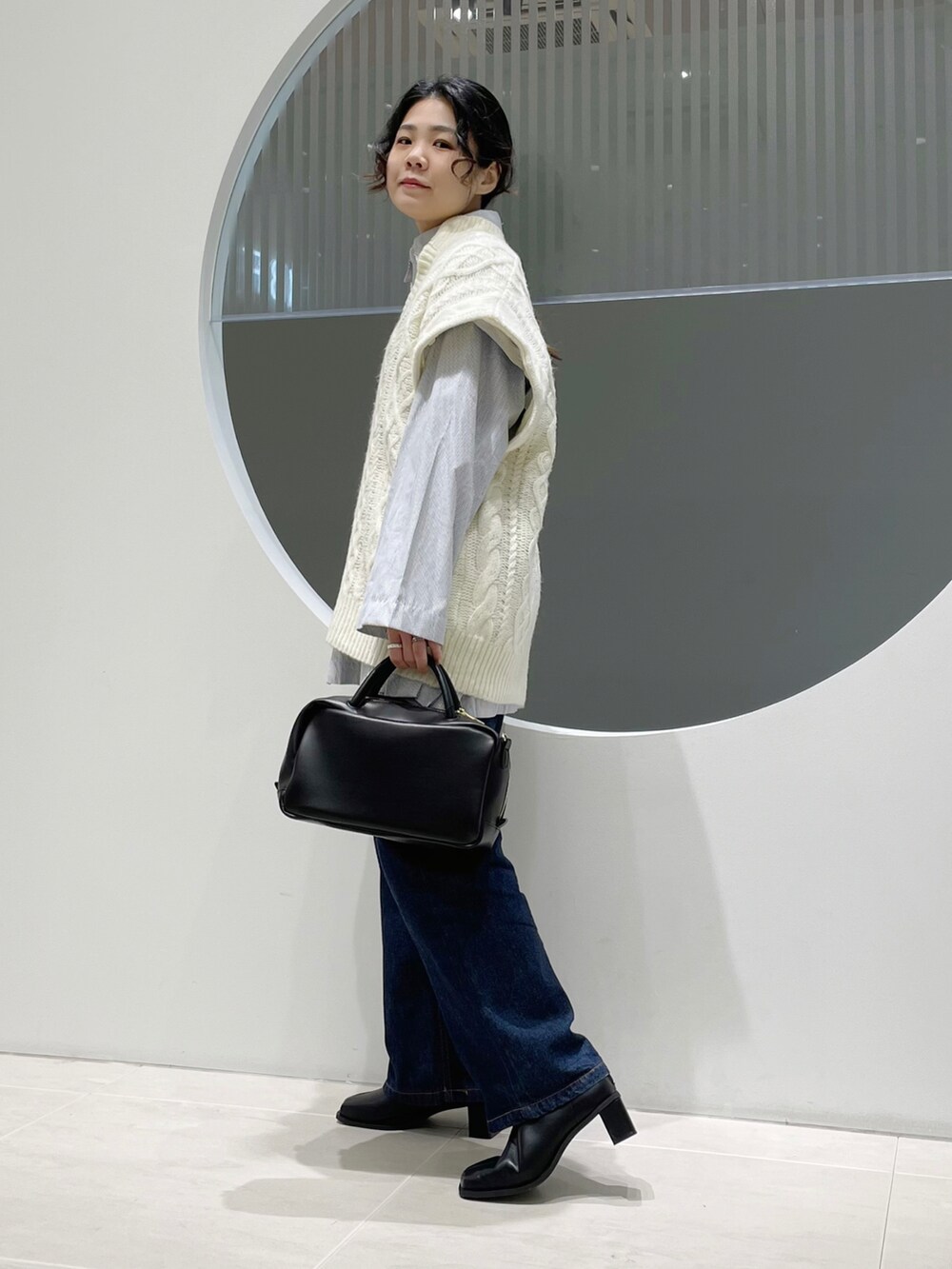 ホワイト系のニット/セーター、ブラック系のボストンバッグ、ブラック系のブーツを着用したレディースの冬コーディネートの2枚目の写真