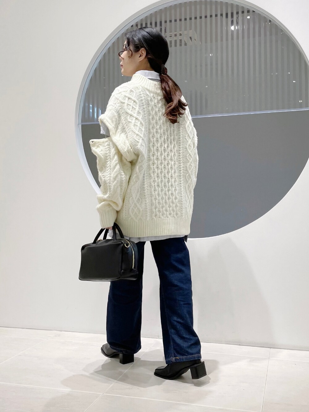 ホワイト系のニット/セーター、ブラック系のボストンバッグ、ブラック系のブーツを着用したレディースの冬コーディネートの3枚目の写真