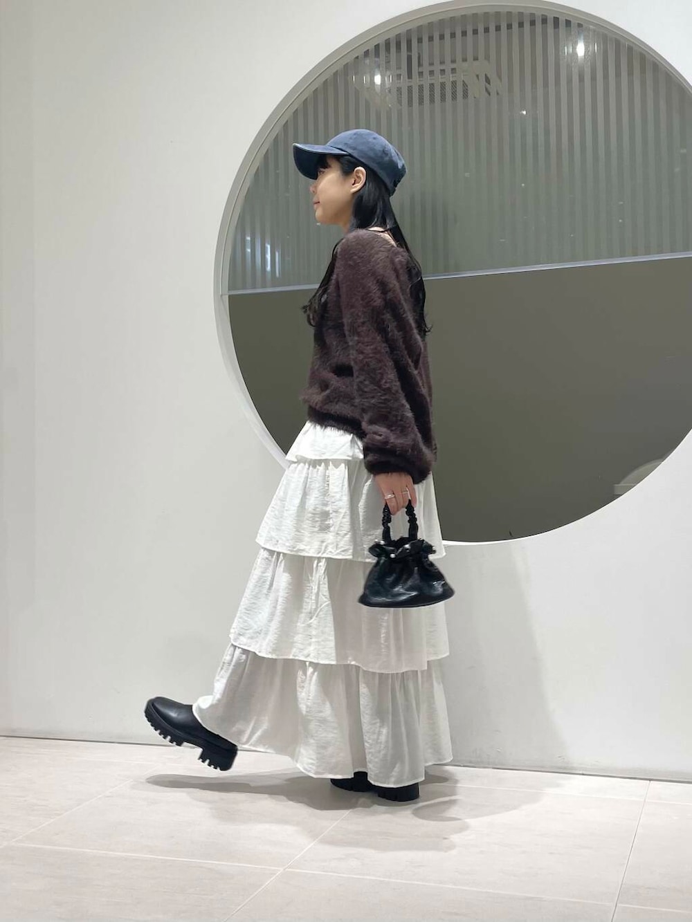 ブラック系のブーツ、ホワイト系のスカート、ブラウン系のニット/セーターを着用したレディースの冬コーディネートの2枚目の写真