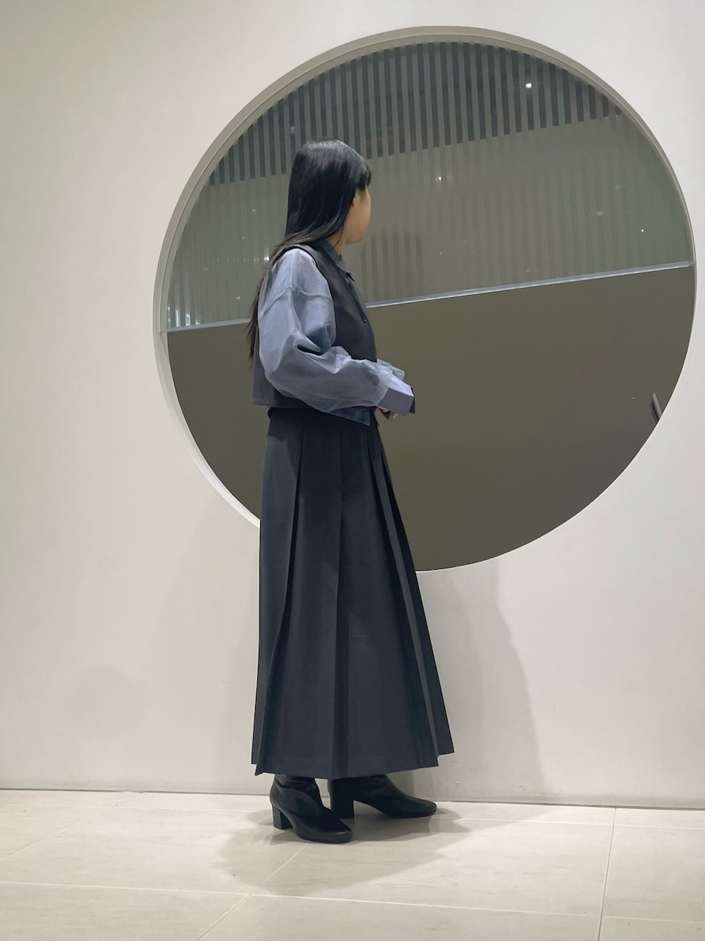 グレー系のワンピース、ブラック系のブーツ、ブルー系のシャツ/ブラウスを着用したレディースの冬コーディネートの2枚目の写真