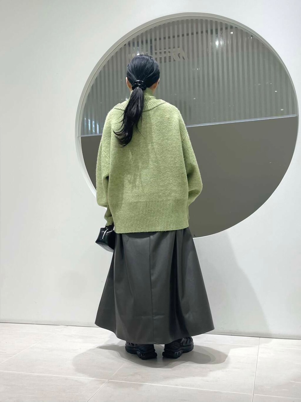 ブラック系のスニーカー、ブラウン系のスカート、グリーン系のニット/セーターを着用したレディースの冬コーディネートの2枚目の写真