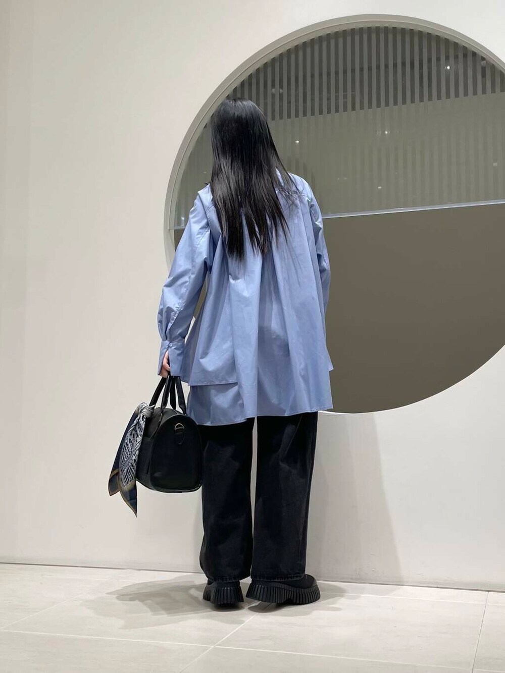 ブラック系のデニムパンツ、ブルー系のワンピース、ブラック系のスニーカーを着用したレディースの冬コーディネートの3枚目の写真