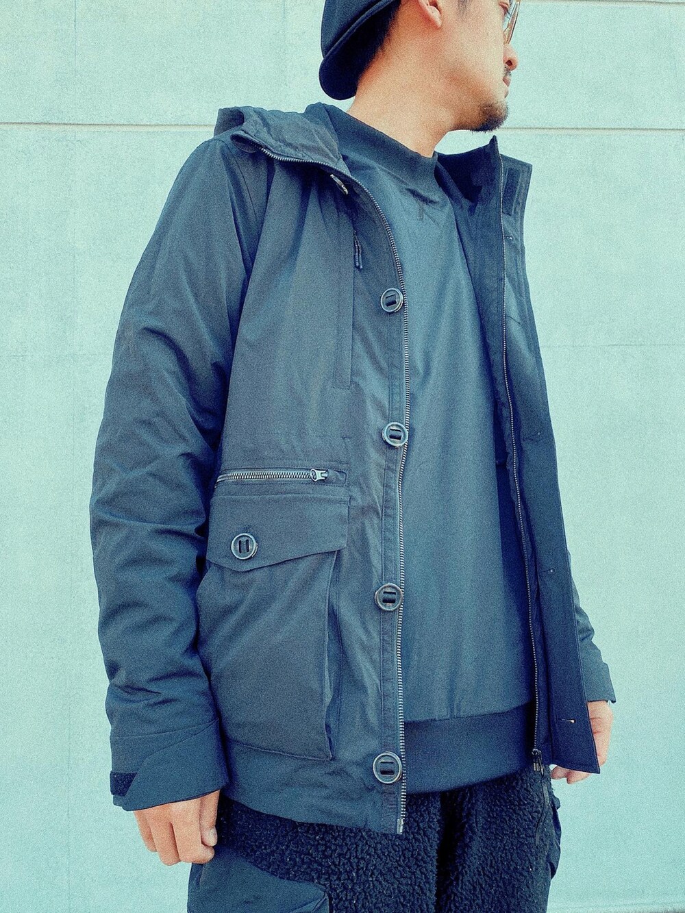 ブラック系のダウンベスト、ブラック系のカーゴパンツ、ブラック系のミリタリージャケットを着用したメンズの冬コーディネートの5枚目の写真