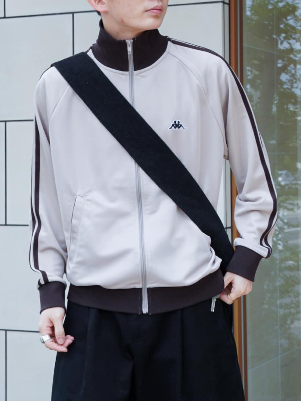 ベージュ系のジャージ、ブラック系のショルダーバッグ、ブラック系のチノパンツを着用したメンズの春コーディネートの4枚目の写真