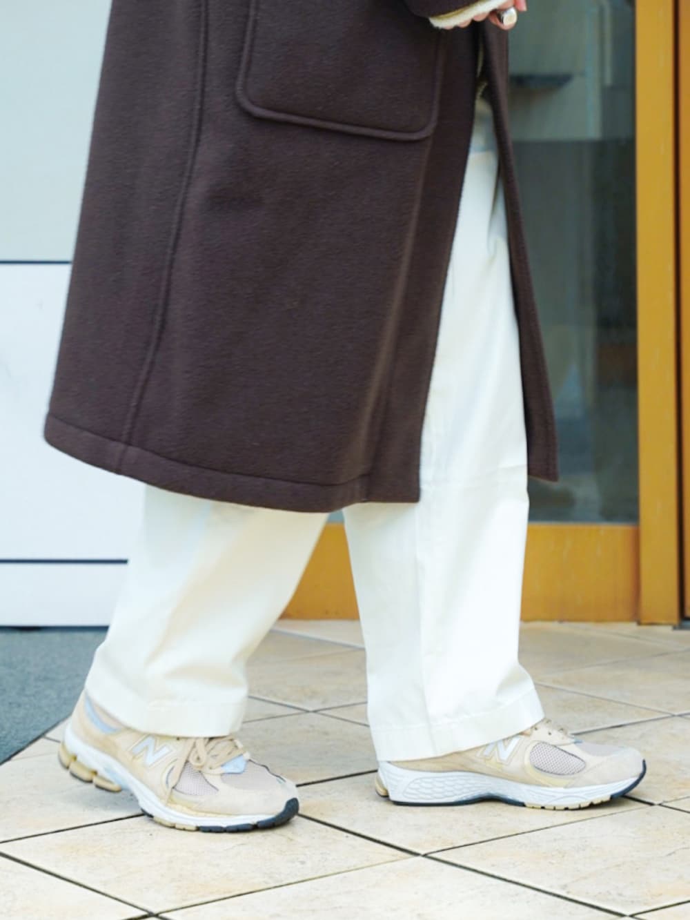 ブラウン系のダッフルコート、ホワイト系のニット/セーター、ベージュ系のショルダーバッグを着用したメンズの冬コーディネートの5枚目の写真